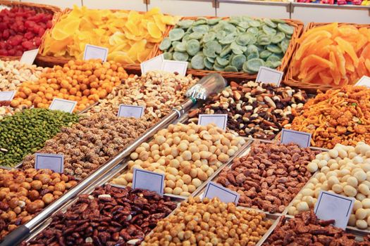 Nuts dried fruits and various snacks on market close up