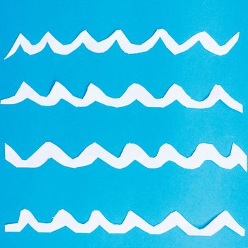 a set of paper waves on a blue surface represent the surface of the sea