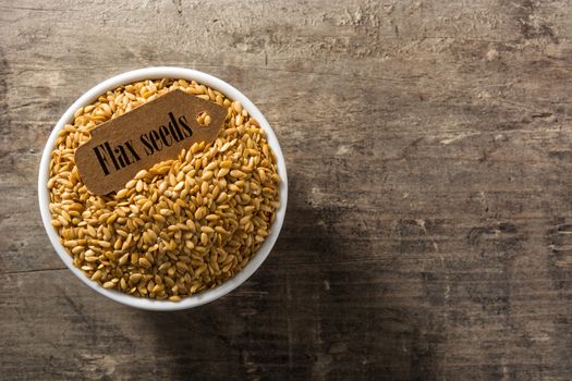 Golden flax seeds in white bowl on wooden table