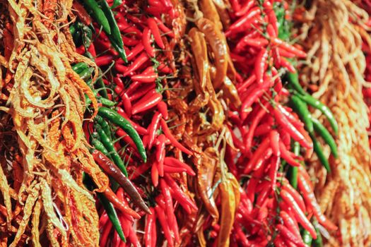 Red green and yellow peppers hanged in a row at the market