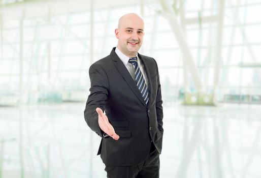 businessman in suit offering to shake the hand, at the office