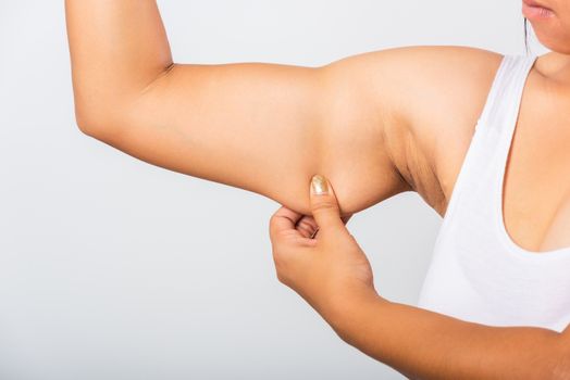 Close up of Asian woman pulling excess fat on her under arm, problem armpit skin, studio isolated on white background, Healthy overweight excess body concept