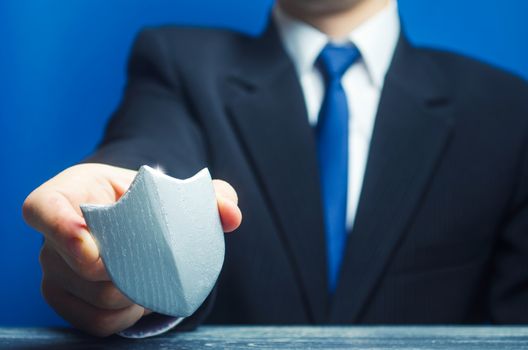 A man holds a protection shield in his hand. Safety, life and property insurance. Security personnel, maintaining law and order. Lawyer defends the rights and innocence. Protectionism, defense