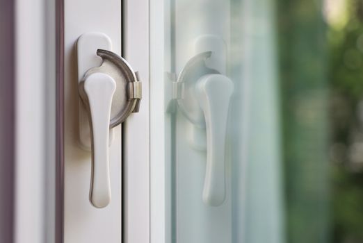 White window lock with mirror reflection. White lever window lock with blurred background.