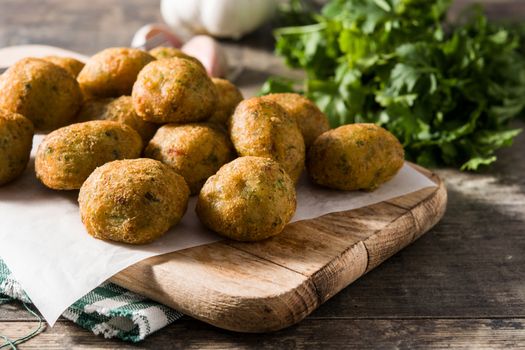 Traditional cod fritters with garlic and parsley on wooden table