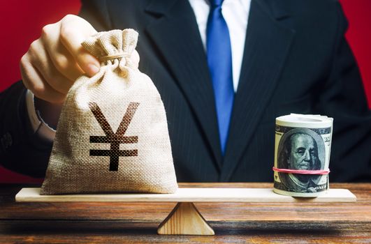 A man puts a Yen yuan money bag on the scales opposite to the dollar. Exchange rate, comparison of economic indicators. Avoiding savings inflation. Investments in foreign currency bonds.