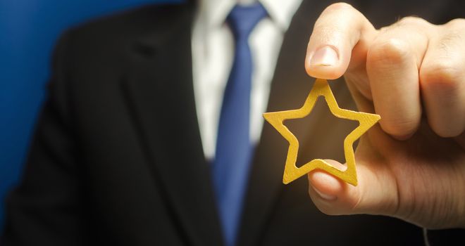 Man holds a golden star in his hand. Symbol of success and excellence. Good reputation, prestige, high recognition. Status, rating. Good ratings and reviews. VIP. Job promotion and career growth.