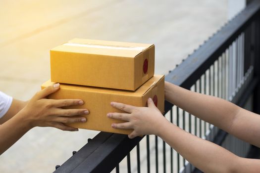 Courier service is delivering the brown box to the recipient. The shipping company delivers the goods to the recipient at the front door.