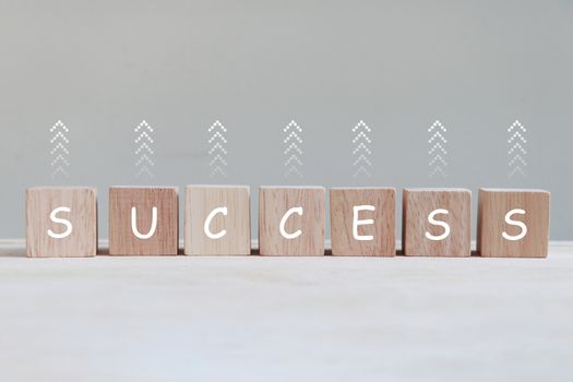 Success letter on wooden cube with up arrow symbol.