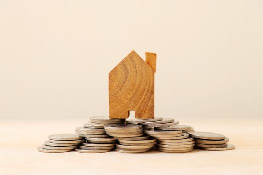 Wooden house model on a pile of coins.