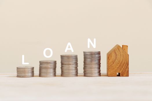 Coins arranged in a bar graph and wooden house model with loan on top.