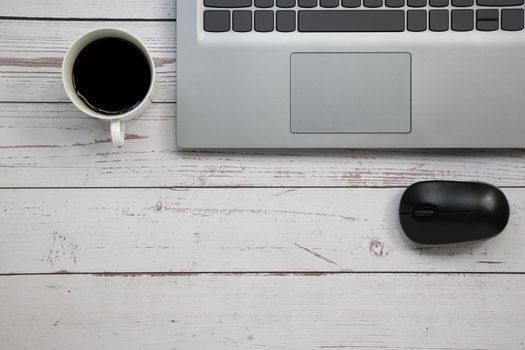 Notebook wireless mouse and a cup of coffee on the white table with copy space.