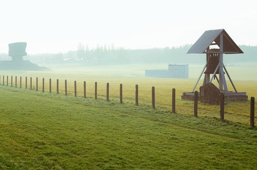 grass field with barbed wire fence and Peace bell in German concentration and extermination camp Majdanek. Lublin, Poland