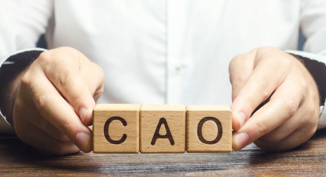 Man holds the word CAO in hands. Manage taxes and payroll. Develop and upgrade finance systems in business. Chief Accounting Officer. Vacancy and duties of a specialist. Financial executives