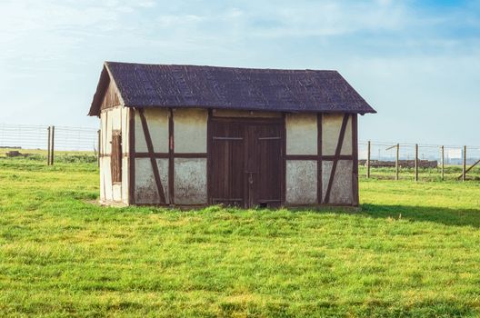 old barn on grassy green field in German concentration and extermination camp Majdanek. Lublin, Poland