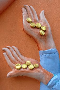 Close up Golden Coins in Sculpture Hand on Concrete Wall.