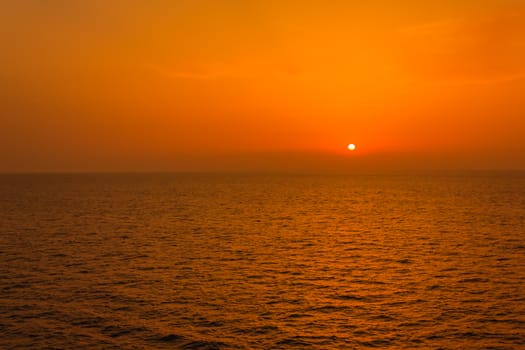 the sunset paints the orange and yellow sky and reflects the colors on the sea