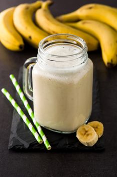 Banana smoothie in jar on black slate background