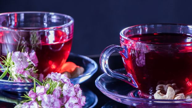 Mugs of red tea with carnation flowers. Zen tea ceremony. Horizontal photo of red herbal Indian medicinal tea. Elegant mugs with a relaxing healing tonic drink and white flowers. English red tea