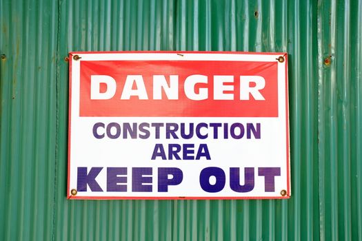 "DANGER CONSTRUCTION AREA KEEP OUT" Sign on Green Zinc Wall Background.