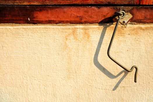 Close-up Old Bended Cabin Hook Latch with Shadow on Concrete Wall.