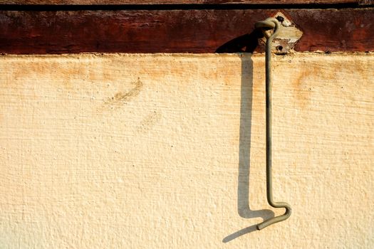 Close-up Old Cabin Hook Latch with Shadow on Concrete Wall.