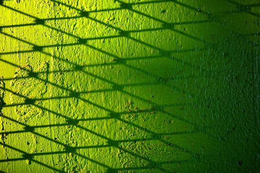 Metal Wire Fence Shadow on Green Concrete Wall Background.