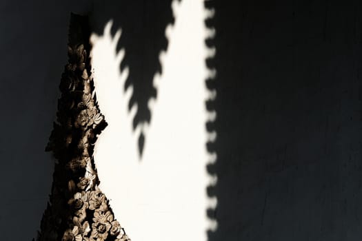 Vintage Thai Sculpture on Concrete Wall with Shadow Background.