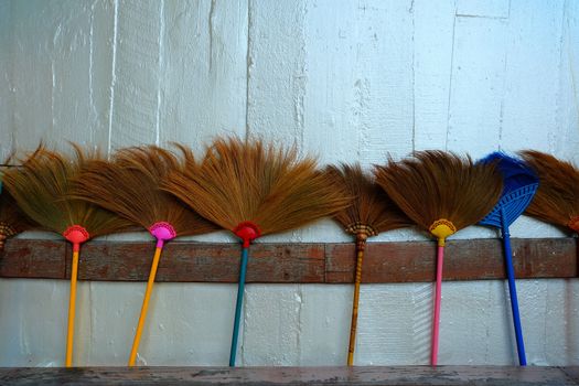 Brooms Leaning Against Silver Concrete Wall.