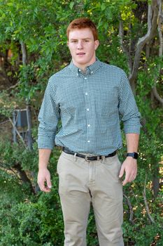 Handsome, red- headed young man posing for his High School graduation photos. Very attractive and athletic looking young boy.