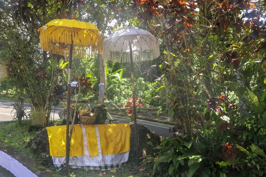 Hindu temple near to Batukaru temple on Bali island in Indonesia. Tabernacle of the Believing Balinese. Balinese culture, closeup of yellow and white decorative umbrelas among tropical plants.