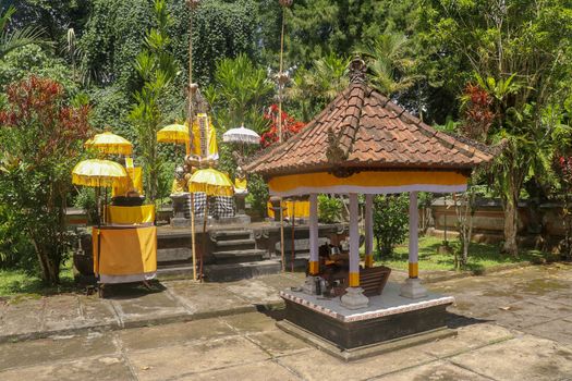Hindu temple near to Batukaru temple on Bali island in Indonesia. Tabernacle of the Believing Balinese. Balinese culture, closeup of yellow and white decorative umbrelas among tropical plants.