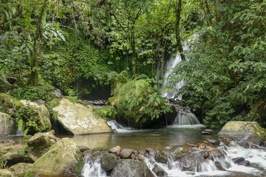 Water Flow Through Stones In Yeh Ho River in tropical jungle. Beautiful waterfall is located in the lush rice field-laden Penebel village in Tabanan near to Jatiluwih rice terrace in Bali, Indonesia.