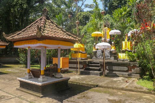 Hindu temple near to Batukaru temple on Bali island in Indonesia. Tabernacle of the Believing Balinese. Balinese culture, closeup of yellow and white decorative umbrelas among tropical plants.