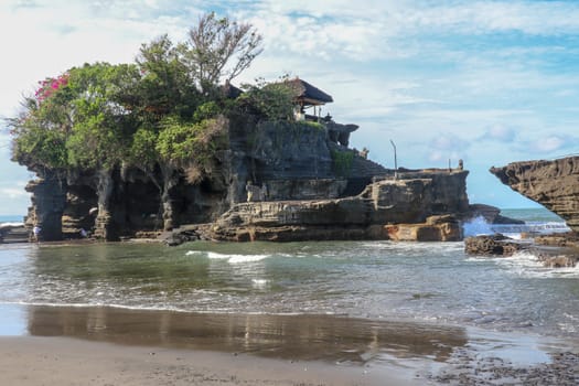 Beautiful balinese landscape. Ancient hinduism temple Tanah lot on the rock against sunset sky. Bali Island, Indonesia. famous Tanah Lot Temple on Sea in Bali Island Indonesia with blue sky and waves.