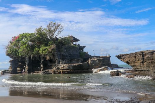 Sacred Balinese temple in Tanah Lot. Pura Batu Bolong on coastline with hole in rock. Traditional style and architecture of Bali. Holy place for local indonesian people