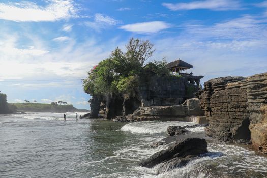Sacred Balinese temple in Tanah Lot. Pura Batu Bolong on coastline with hole in rock. Traditional style and architecture of Bali. Holy place for local indonesian people