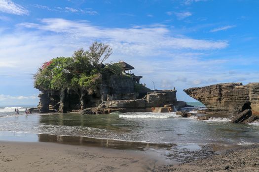 Sacred Balinese temple in Tanah Lot. Pura Batu Bolong on coastline with hole in rock. Traditional style and architecture of Bali. Holy place for local indonesian people