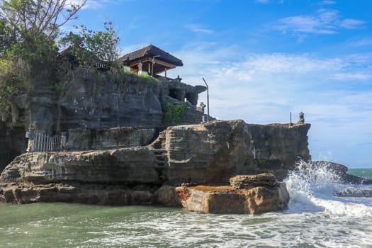 Beautiful balinese landscape. Ancient hinduism temple Tanah lot on the rock against sunset sky. Bali Island, Indonesia. famous Tanah Lot Temple on Sea in Bali Island Indonesia with blue sky and waves.
