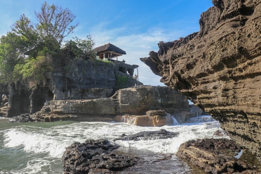 Beautiful balinese landscape. Ancient hinduism temple Tanah lot on the rock against sunset sky. Bali Island, Indonesia. famous Tanah Lot Temple on Sea in Bali Island Indonesia with blue sky and waves.