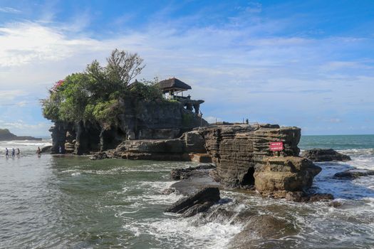 Sacred Balinese temple in Tanah Lot. Pura Batu Bolong on coastline with hole in rock. Traditional style and architecture of Bali. Holy place for local indonesian people