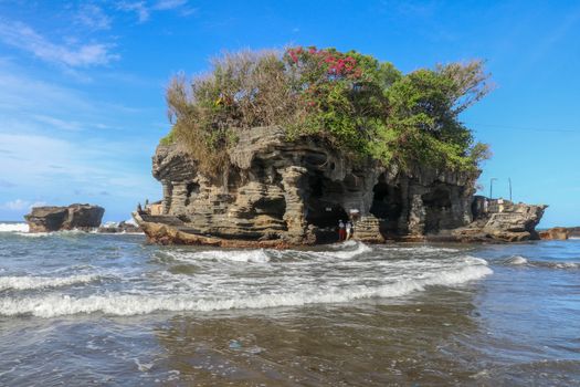 Sacred Balinese temple in Tanah Lot. Pura Batu Bolong on coastline with hole in rock. Traditional style and architecture of Bali. Holy place for local indonesian people