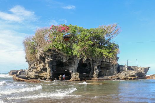 Sacred Balinese temple in Tanah Lot. Pura Batu Bolong on coastline with hole in rock. Traditional style and architecture of Bali. Holy place for local indonesian people