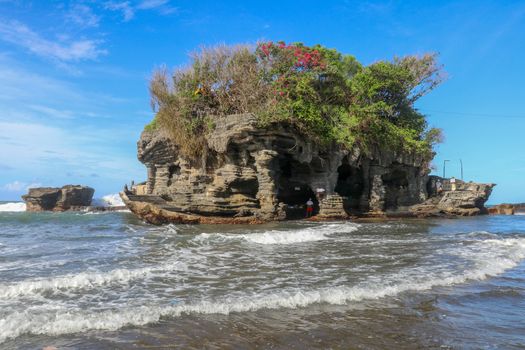 Sacred Balinese temple in Tanah Lot. Pura Batu Bolong on coastline with hole in rock. Traditional style and architecture of Bali. Holy place for local indonesian people