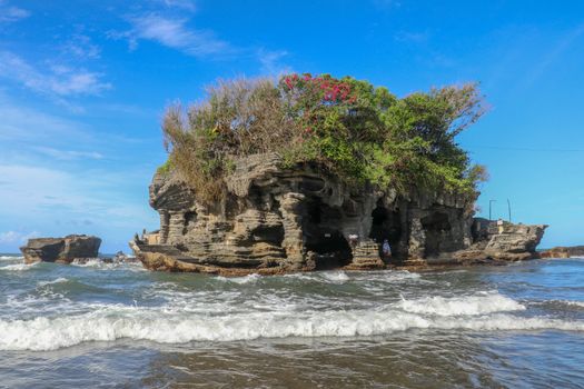Sacred Balinese temple in Tanah Lot. Pura Batu Bolong on coastline with hole in rock. Traditional style and architecture of Bali. Holy place for local indonesian people