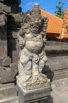 Closeup of stone statue in Temple Batu Bolong near to Tanah Lot in Bali, Indonesia. A carved statue with fine details that stands outside the entrance to Hindu temple as a guardian. Balinese culture.
