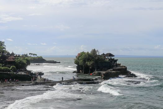 Indian Ocean coast near the Sacred Balinese temple Tanah Lot. Pura Batu Bolong on the edge of a cliff at coastline with hole in the rock. Holy place for local indonesian people