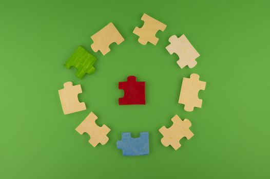 Pieces of colorful wooden puzzle randomly lying on green background surface, viewed from high angle