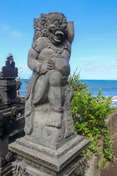 Closeup of stone statue in Temple Batu Bolong near to Tanah Lot in Bali, Indonesia. A carved statue with fine details that stands outside the entrance to Hindu temple as a guardian. Balinese culture.