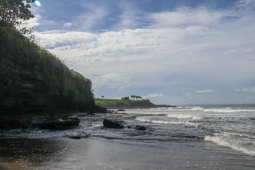 Indian Ocean coast near the Sacred Balinese temple Tanah Lot. Pura Batu Bolong on the edge of a cliff at coastline with hole in the rock. Holy place for local indonesian people